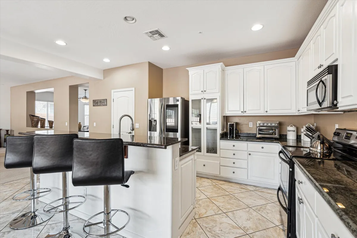 A modern kitchen featuring island seating, stainless steel appliances, and granite countertops. The space is bright and inviting, ideal for casual breakfasts or entertaining guests, with an open layout that encourages social interaction.