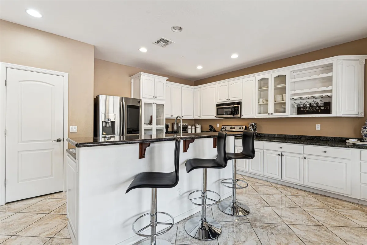 A stylish and spacious kitchen with a prominent central island surrounded by bar stools, stainless steel appliances, and sleek cabinetry. The scene is set for cooking, entertaining, and socializing, with ample counter space and a welcoming atmosphere.