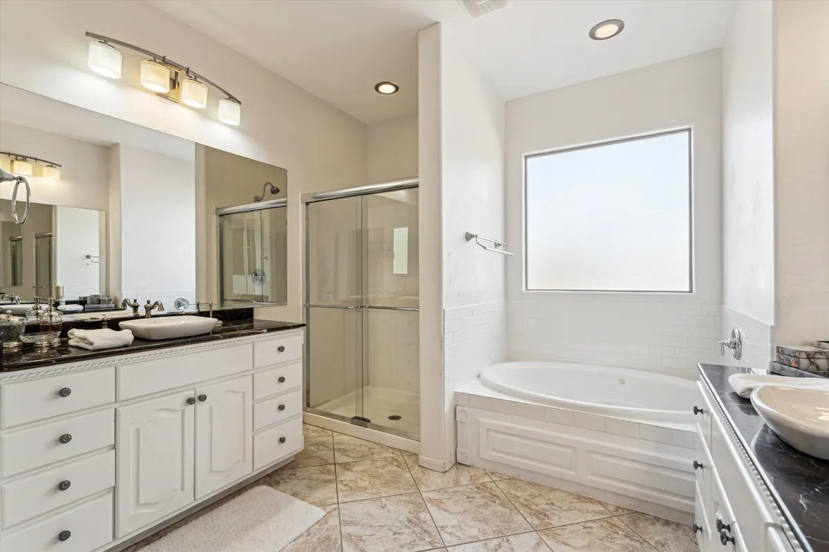 A spa-inspired bathroom featuring a deep soaking tub, a modern walk-in shower, a double-sink vanity, and a large mirror. The space exudes tranquility and luxury, bathed in natural light, and designed for both relaxation and efficient routines.