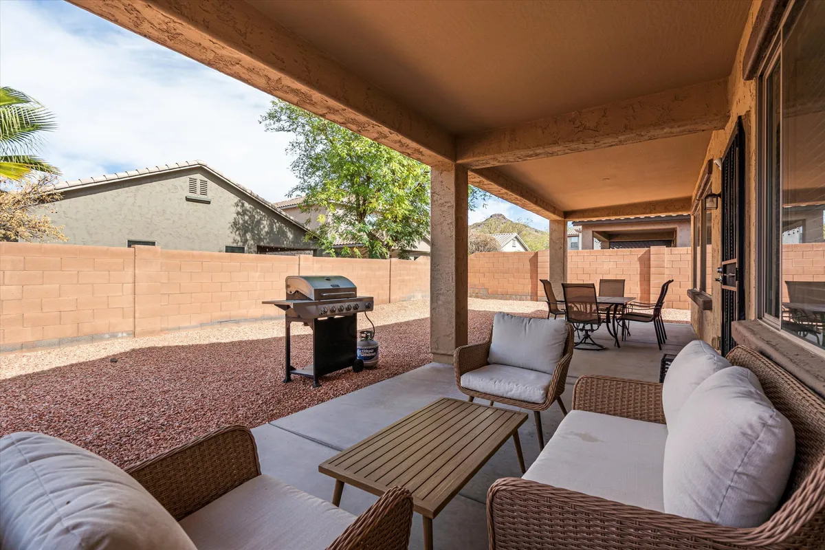 An inviting exterior view showing an outdoor seating area, a dining table, and a grill, set up for barbecuing and socializing. The furniture is arranged to encourage conversation and group meals, with plenty of space for movement and activities.