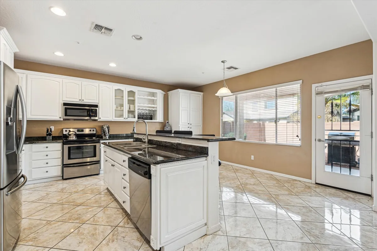 A bright, welcoming kitchen showcasing a large kitchen island, stainless steel appliances, and abundant natural light from expansive windows. The setup is perfect for cooking together or hosting festive gatherings.