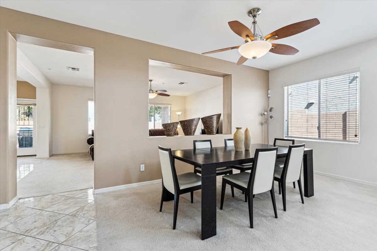 A modern, cozy dining area with a central table, decorative vases, and an overhead ceiling fan. The space is set up for family meals, entertaining guests, and memorable gatherings, radiating warmth and sophistication.