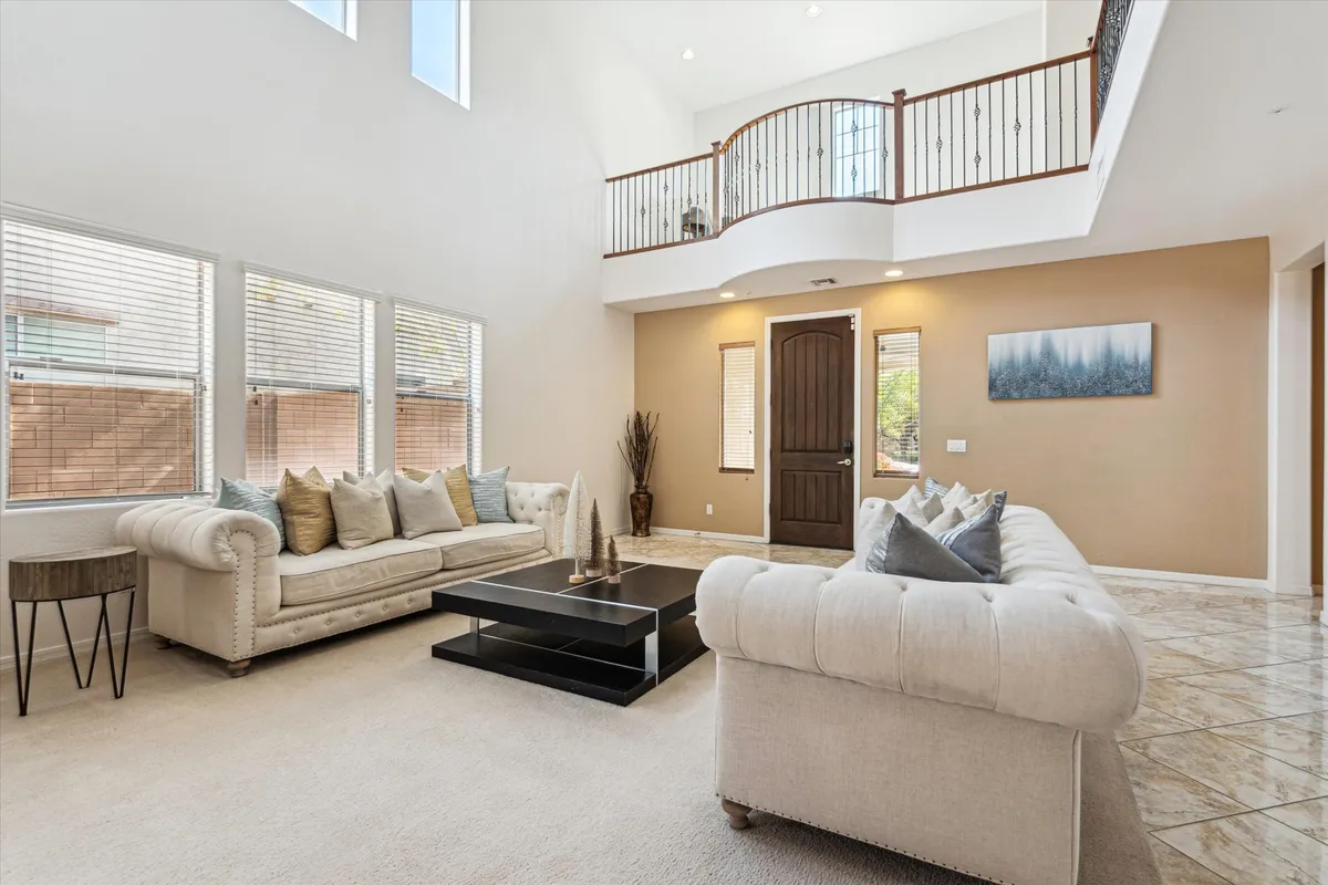 A cozy living room scene featuring a large sectional sofa, a centrally placed coffee table, and a welcoming entrance with a staircase in the background. The setup is ideal for social gatherings, family conversations, and movie nights.