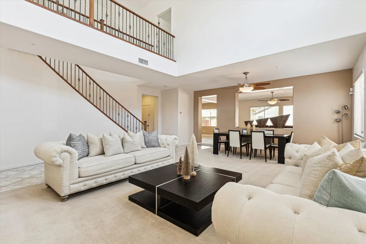 This inviting interior image shows a comfortable sofa and coffee table with a view of the adjacent dining area and staircase. The open layout is perfect for entertaining, family gatherings, and creating lasting memories.