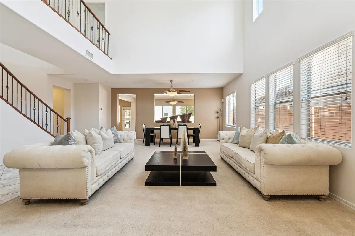 The image showcases a spacious, sunlit open-plan living and dining area with plush, comfortable sofas arranged for conversation or movie nights, a stylish coffee table, and an inviting dining space perfect for gatherings. The decor is modern yet warm, creating a welcoming and relaxed atmosphere ideal for groups or families.